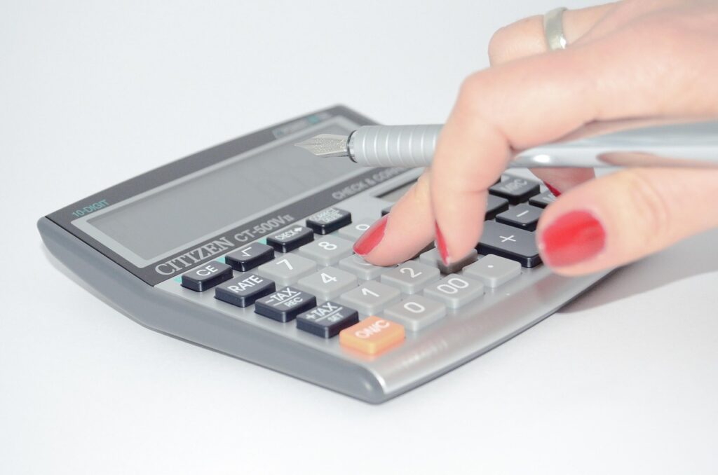 fingers with red nail polish press a calculator