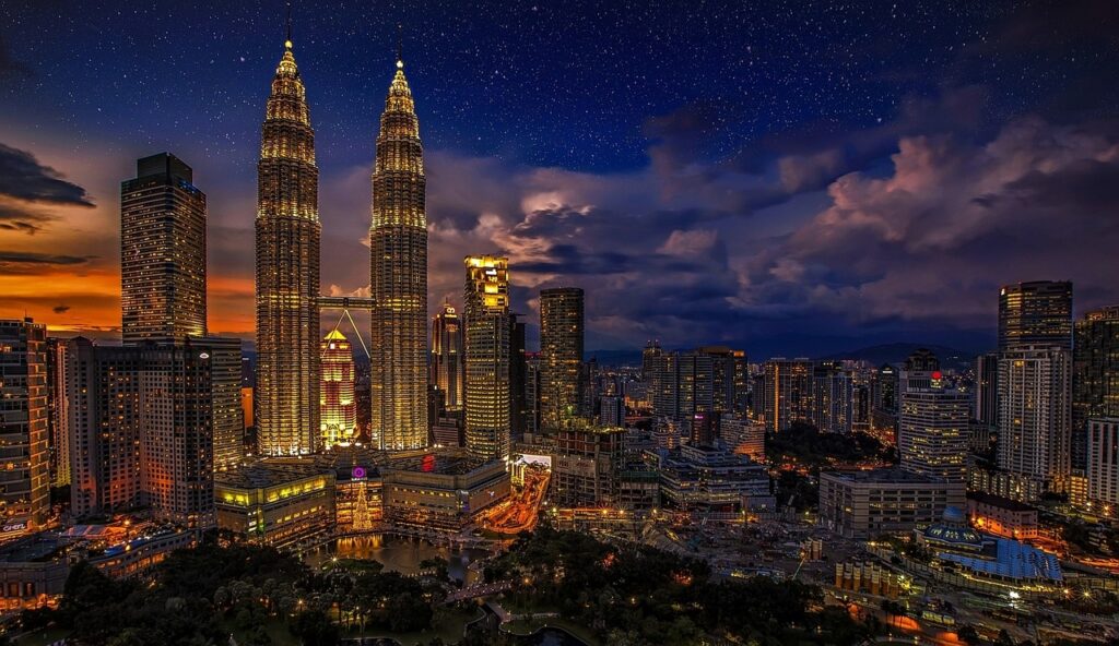 The Petronas Towers dominate the city skyline under a dramatic sunset