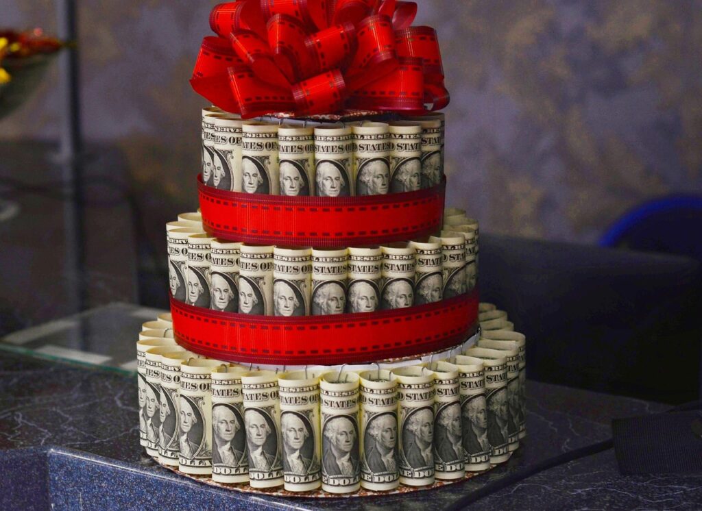 A cake made out of dollar bills and red ribbon