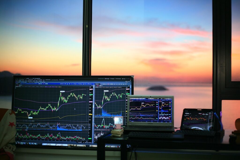A view of a sunrise through a window in the background, with various screens showing charts in the foreground.