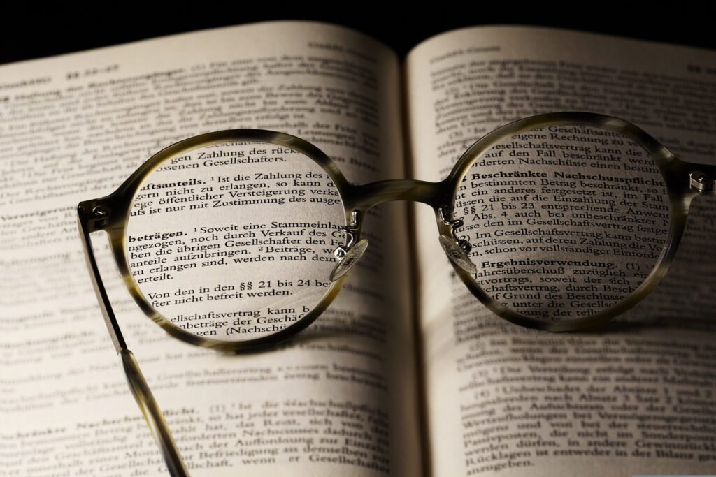 A pair of reading glasses sits on top of an open book.